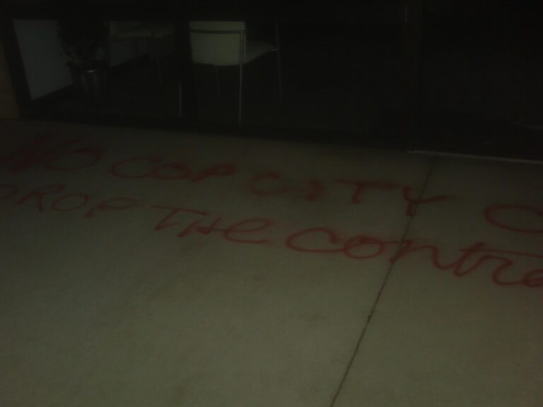 Graffiti on concrete reading "No Cop City CLT (Charlotte), "Drop the Contract"